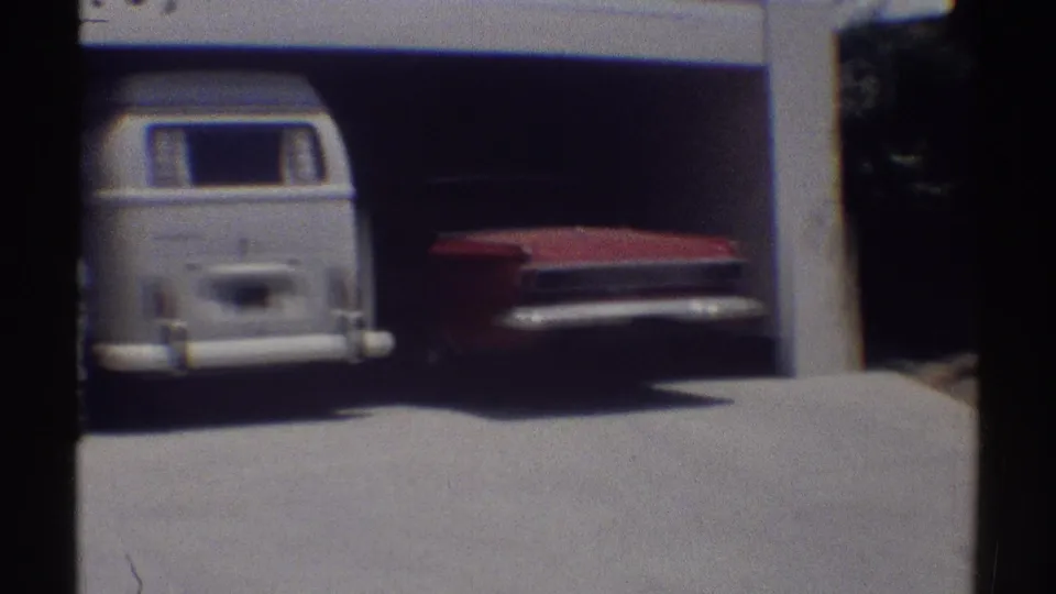 1969 Woodland Hills home-movie view of a white van and red sedan parked in a shaded residential garage.