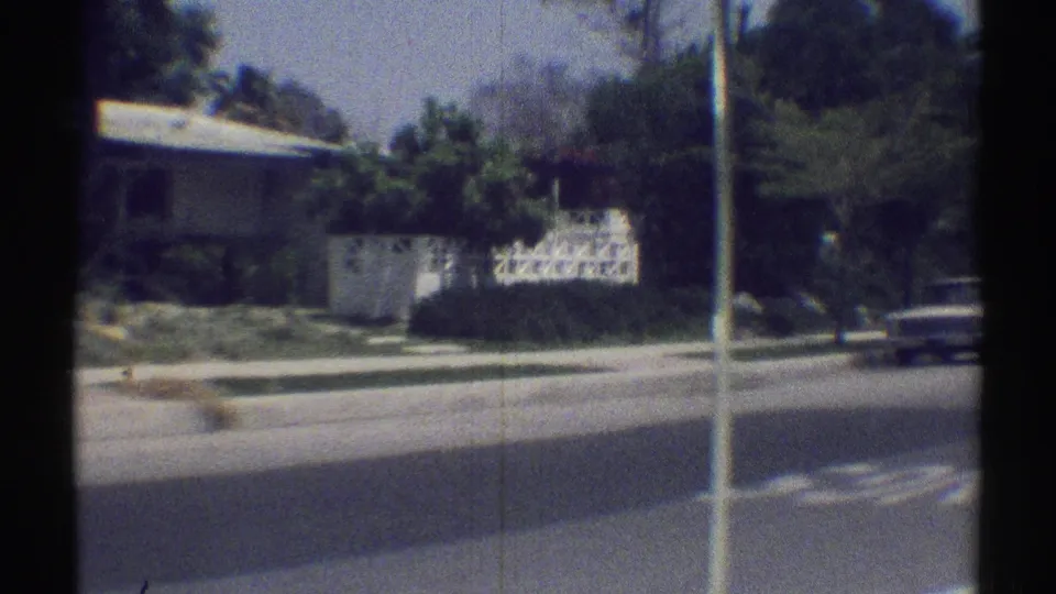 Woodland Hills residential corner in 1969, showing a low house, sidewalk, trees, utility pole, and a car at the edge of frame.