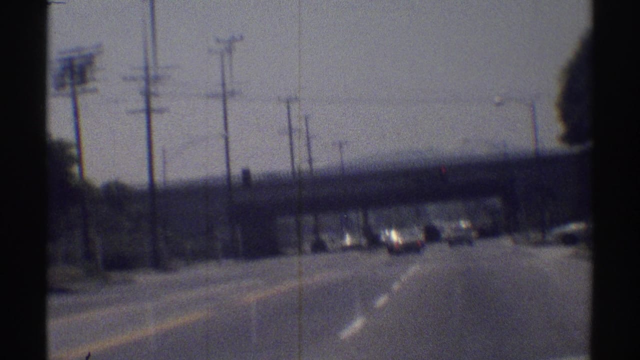 Multi-lane road with cars approaching a concrete overpass and utility poles.