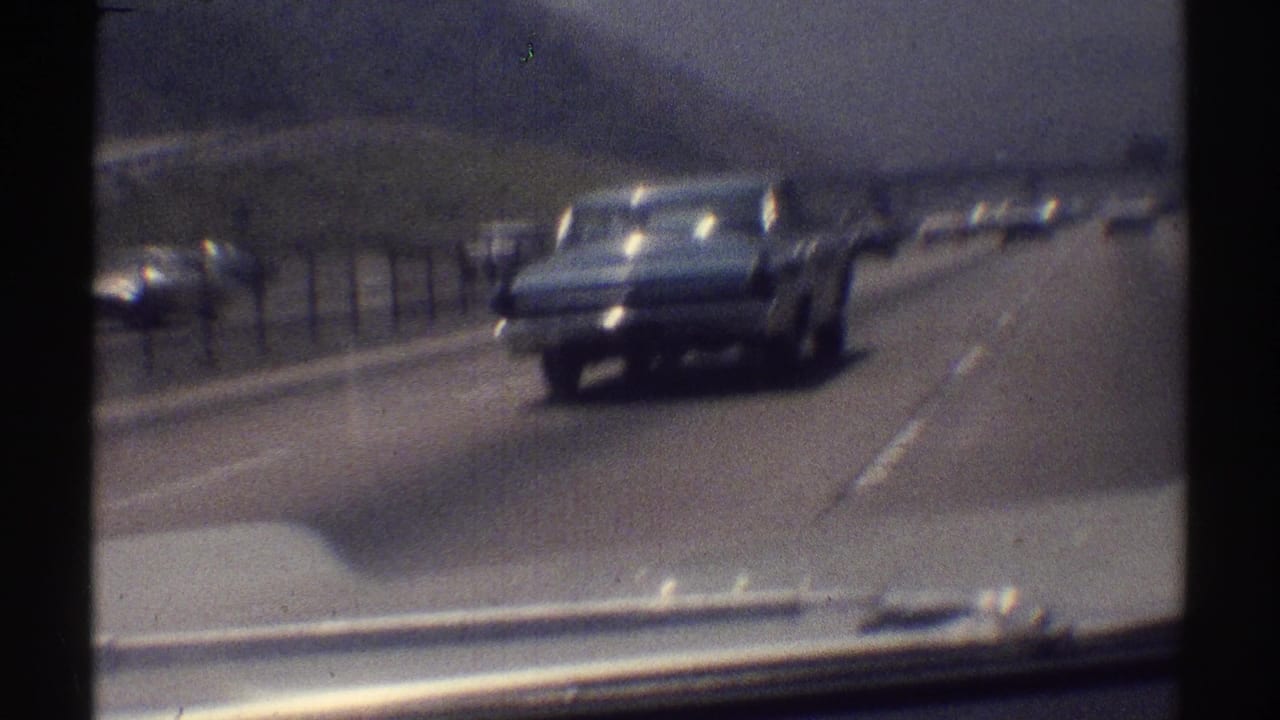 Classic sedan traveling ahead on the highway as other cars follow in adjacent lanes.