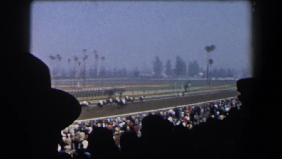 A 1958 California racetrack view shows horses running past while foreground spectators remain in dark silhouette.