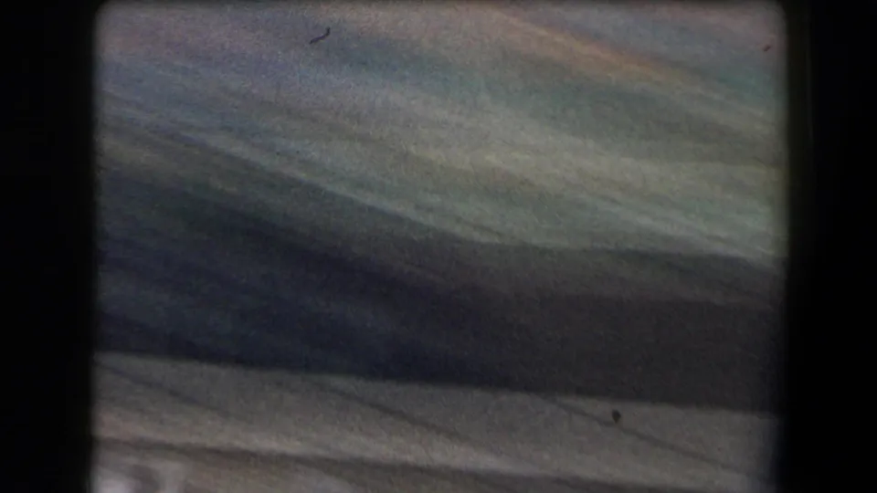 Brief blurred 8mm frame from the horse-race clip, likely caused by camera movement during the spectator-shot sequence.
