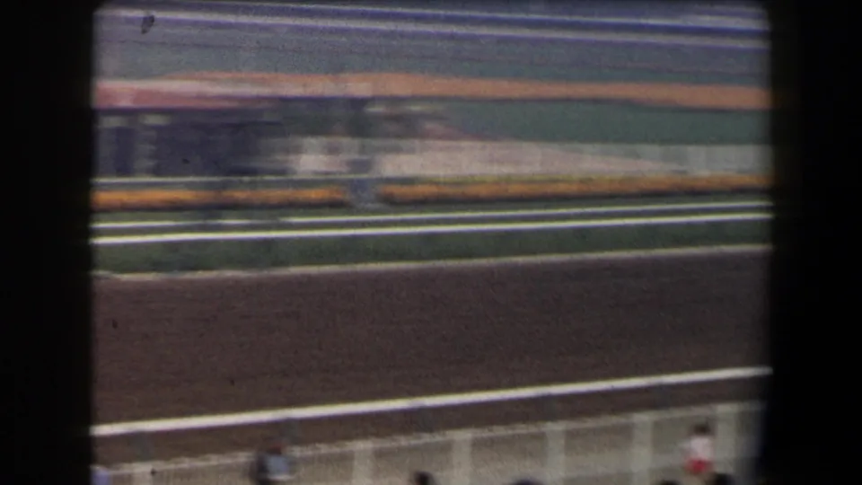 Late-1950s California racetrack view with motion blur across the track and spectators near the lower rail.