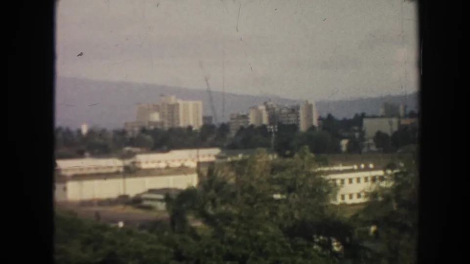 1961 Hawaii 8mm frame showing a coastal city panorama with high-rises, greenery and distant mountains.