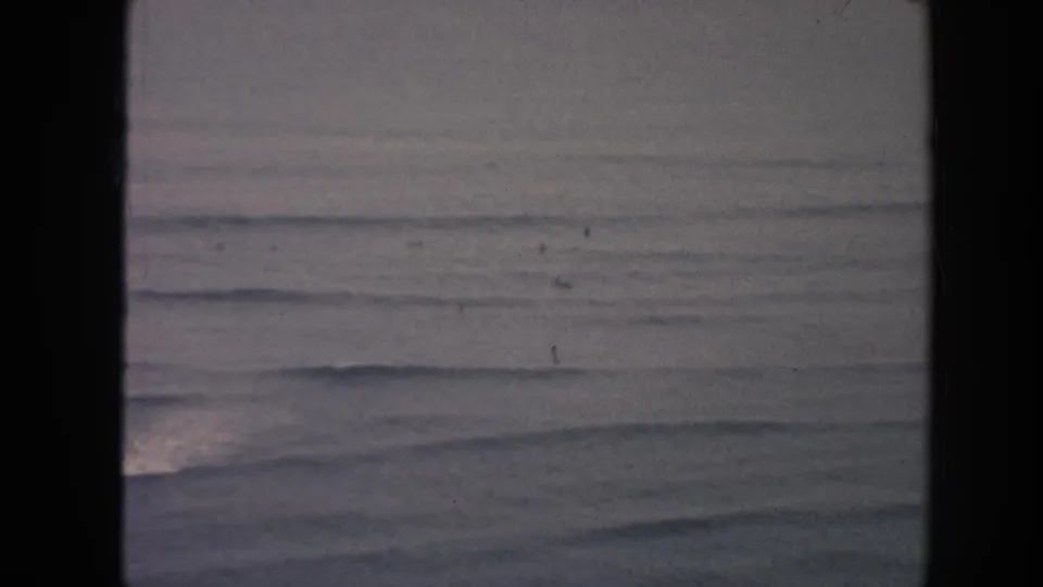 1961 Hawaii 8mm frame showing muted ocean swells beneath a gray overcast sky, with visible film gate borders.