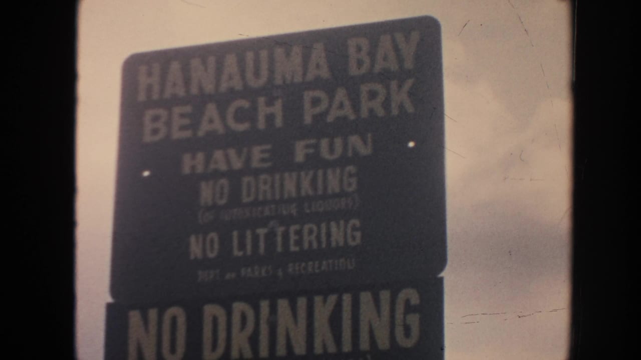 1961 Hawaii 8mm frame showing a Hanauma Bay Beach Park rules sign under cloudy sky.