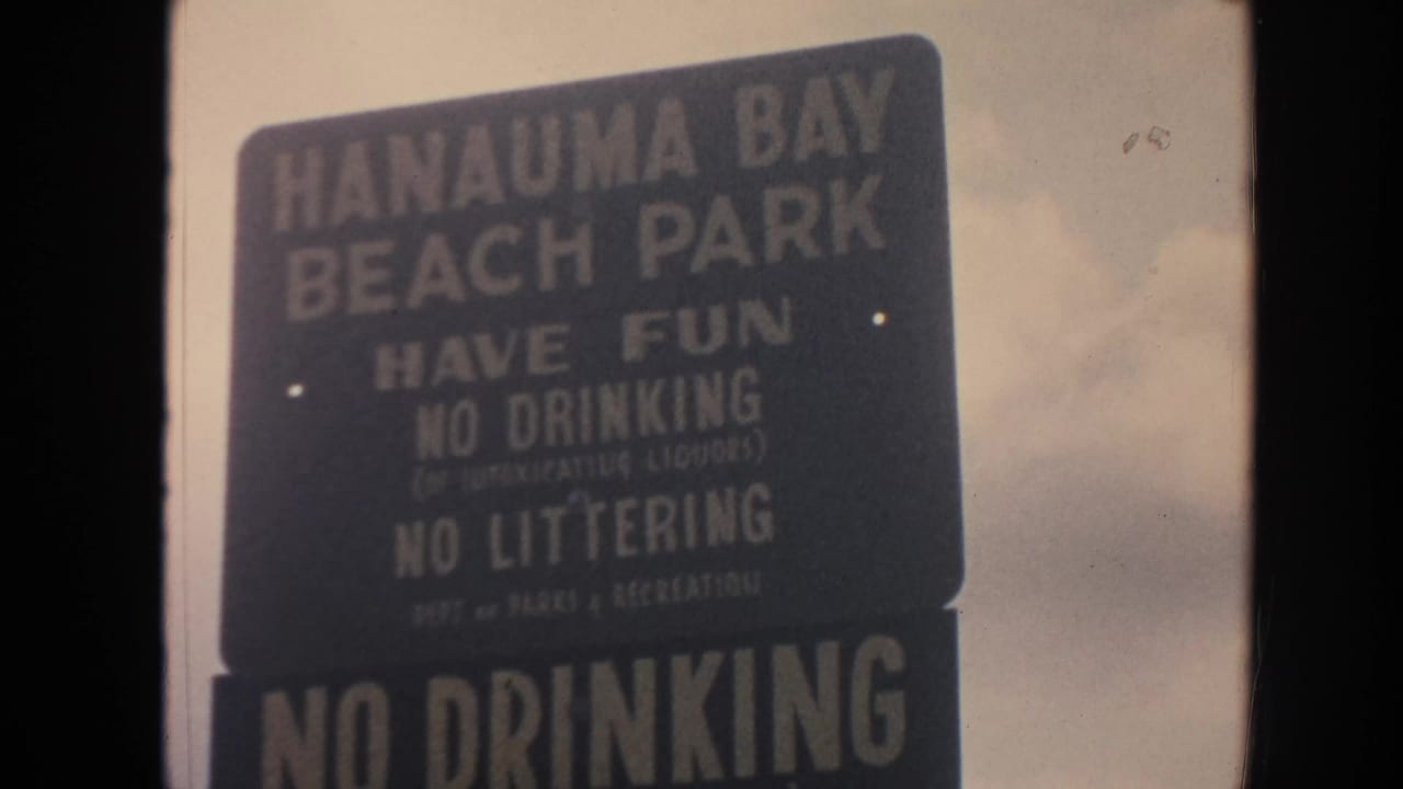 1961 Hawaii home-movie frame with the Hanauma Bay Beach Park sign and readable rules text.