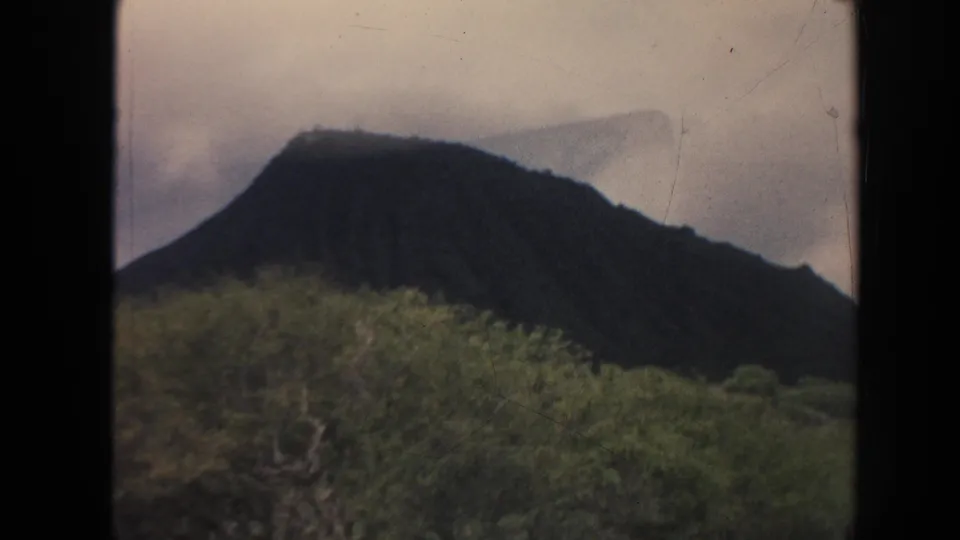 1961 Hawaii 8mm frame showing a green Oahu hillside below a dark volcanic ridge.