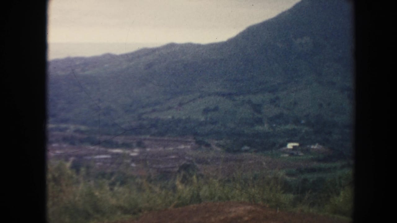 Green valley and mountain slopes with a small white building in the distance.