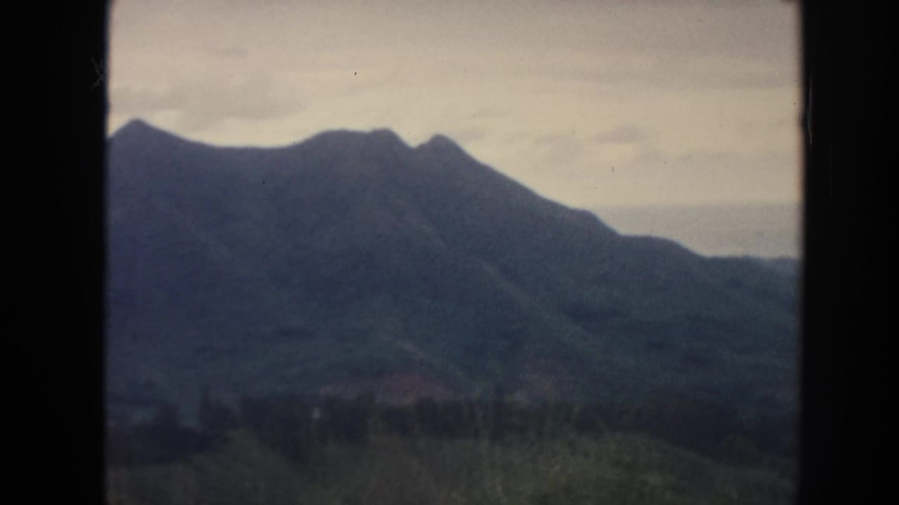 1961 Hawaii home-movie view of a broad mountain range and distant valley under muted cloud cover.