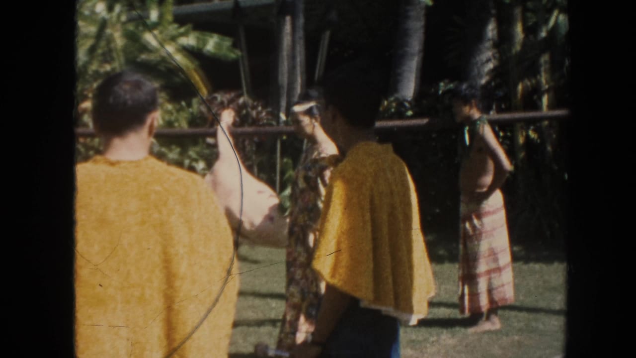 People stand around a pole-borne animal carcass in a tropical outdoor setting.
