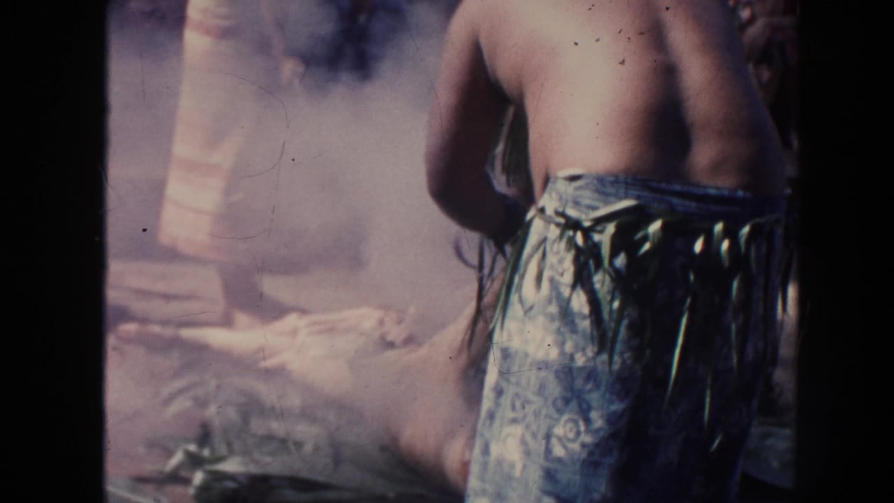 Barefoot performer in a patterned wrap stands near smoke and coals.