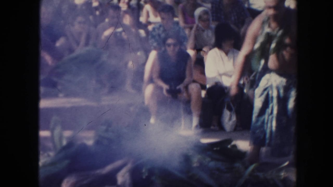 Smoke rises from leaves as onlookers sit behind the activity.