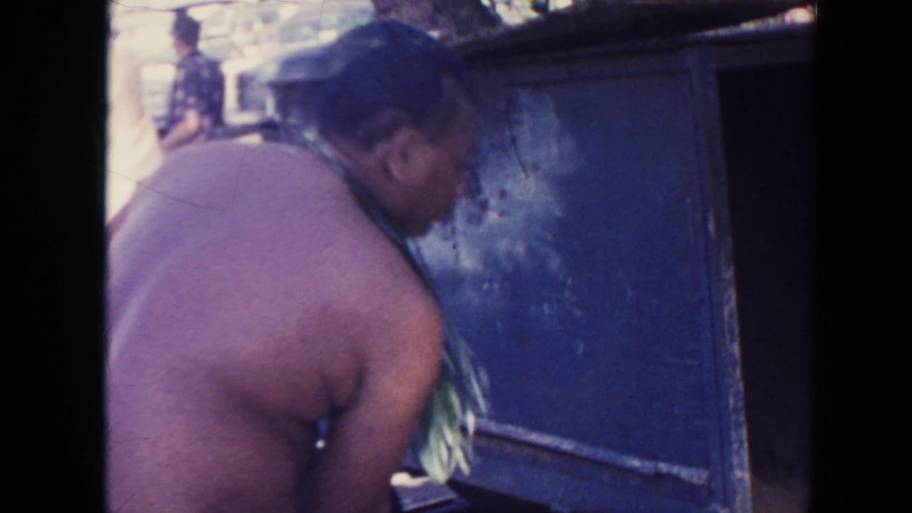 1961 Hawaii 8mm frame showing a man leaning beside a vintage bus, with soft focus and dark film-frame borders.