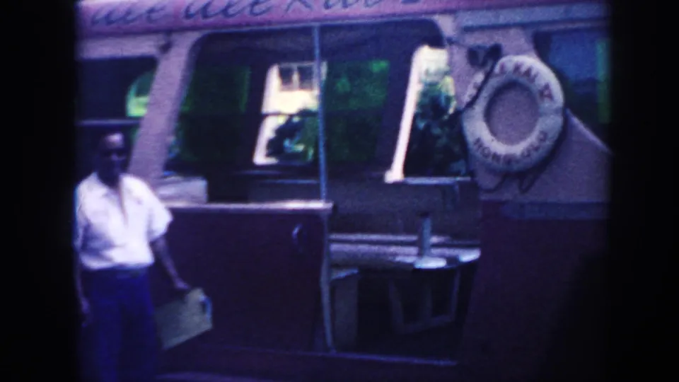 1961 Hawaii 8mm frame showing a man beside the bus entrance, with a life preserver mounted near the doorway.