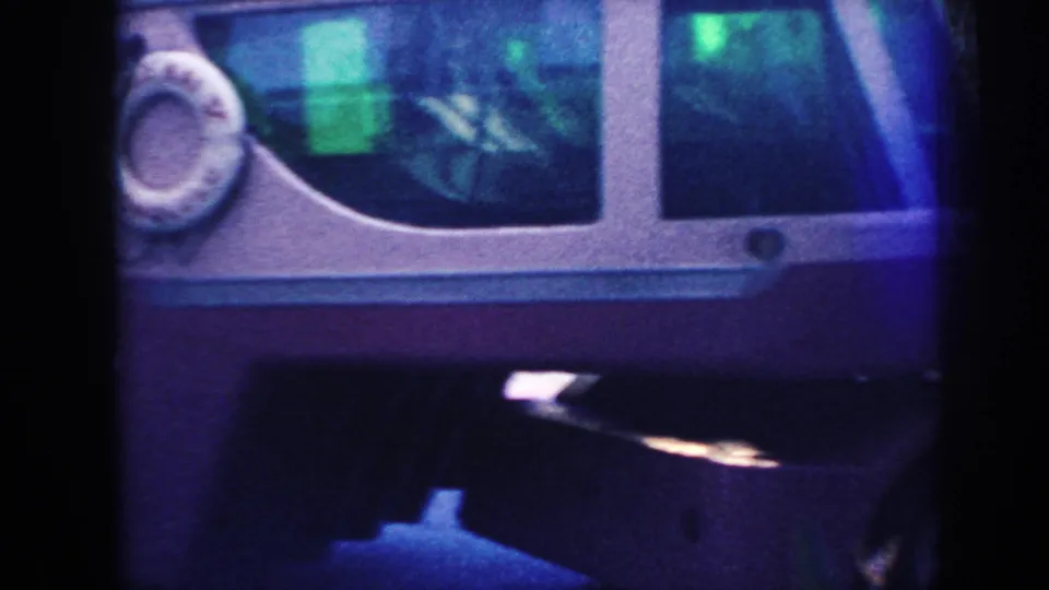 1961 Hawaii frame focused on the vintage bus side, showing windows, faded paint, and part of a life preserver.