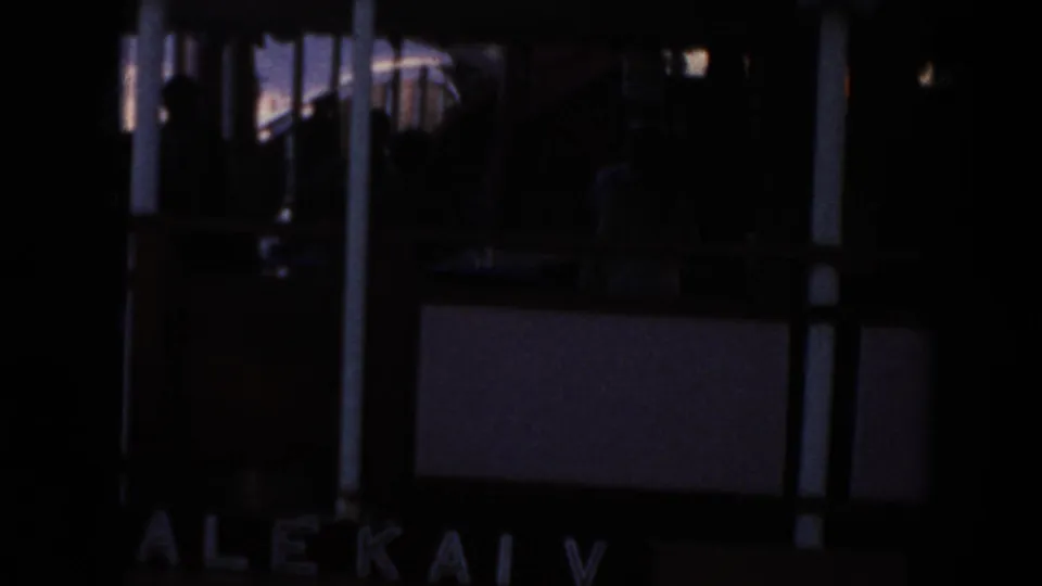 Dark 1961 Hawaii 8mm frame showing a docked boat area with partial Alekai V lettering and silhouetted railings.