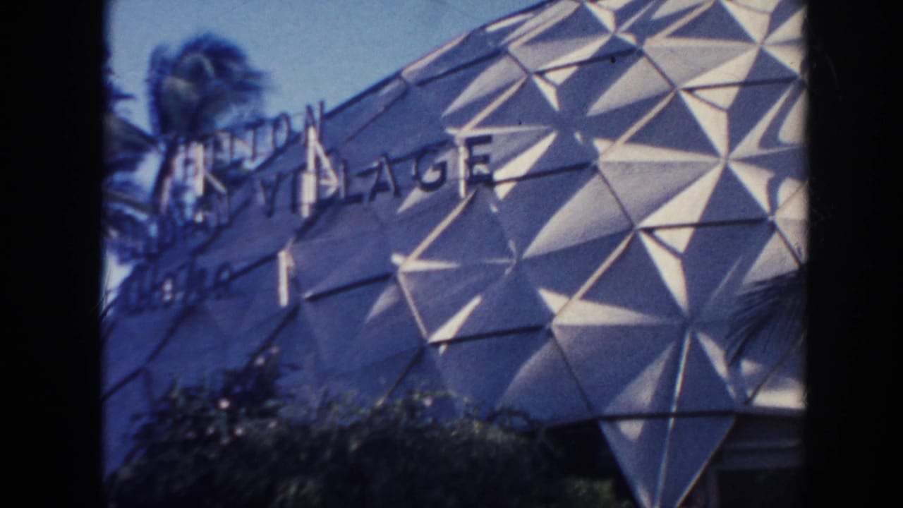 1961 Hawaii frame with partial Hilton Hawaiian Village signage across a geometric dome facade beside palm trees.