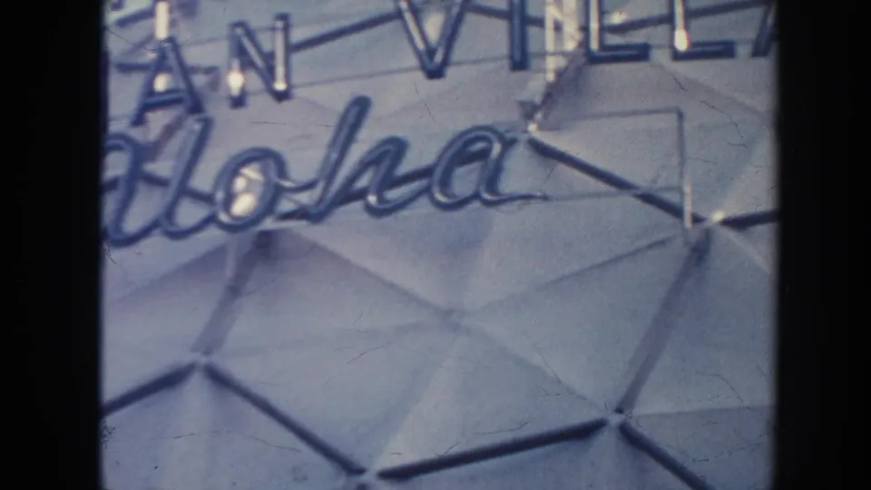 Close 1961 Hawaii frame of Aloha script and partial hotel lettering on the Hilton Hawaiian Village dome facade.