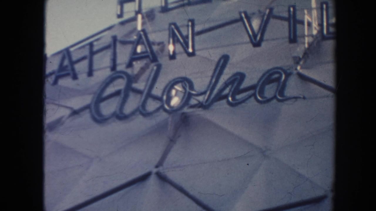 1961 Hawaii 8mm frame showing Hilton Hawaiian Village signage with Aloha script on a gray tiled facade.
