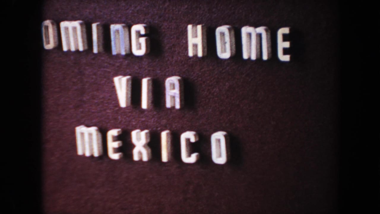 Close 8mm frame of the same travel title card, with raised white letters against a dark background.