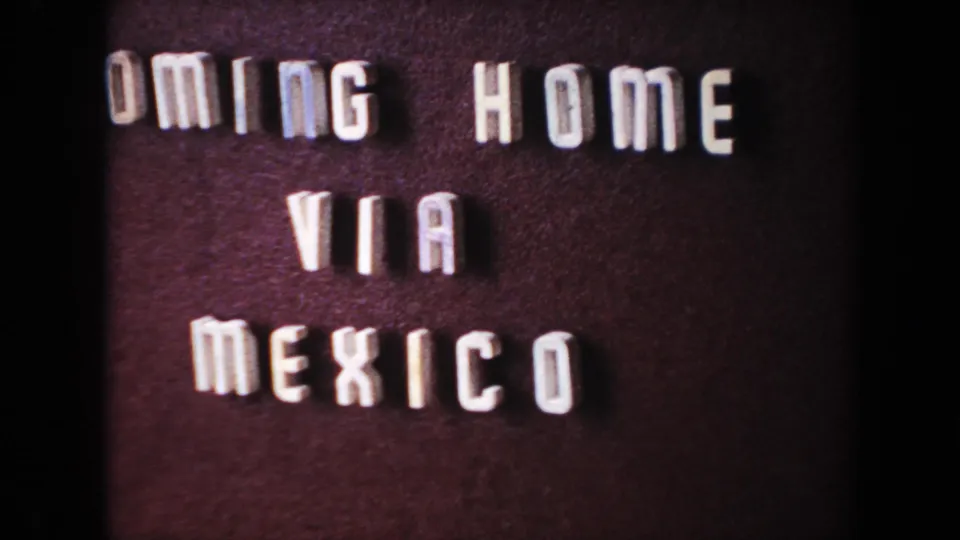 Close 8mm frame of the same travel title card, with raised white letters against a dark background.