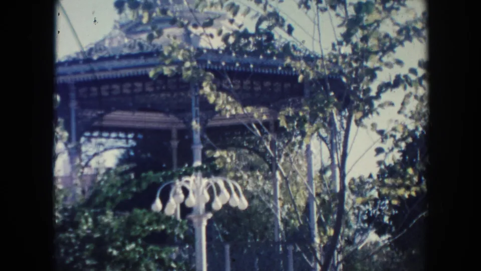 Hawaii 1961 exterior courtyard frame showing leafy trees, a pavilion or gazebo-like structure, and a white ornamental lamppost.
