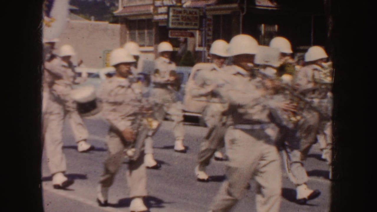Uniformed band members with saxophones and brass instruments move through a sunlit South Dakota street parade.