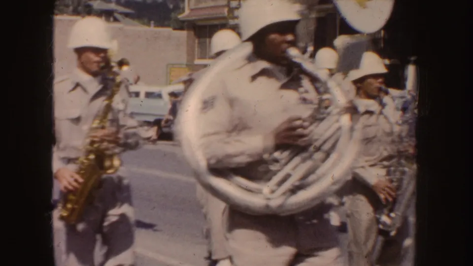 Close curbside view of a sousaphone player and nearby saxophonists during the 1954 South Dakota parade.