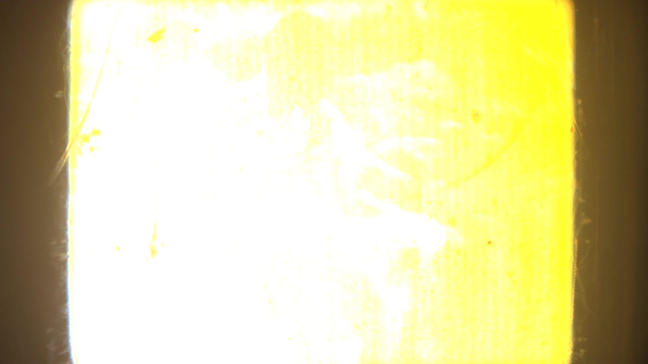 Overexposed yellow 8mm frame with visible film texture and little readable scene detail.