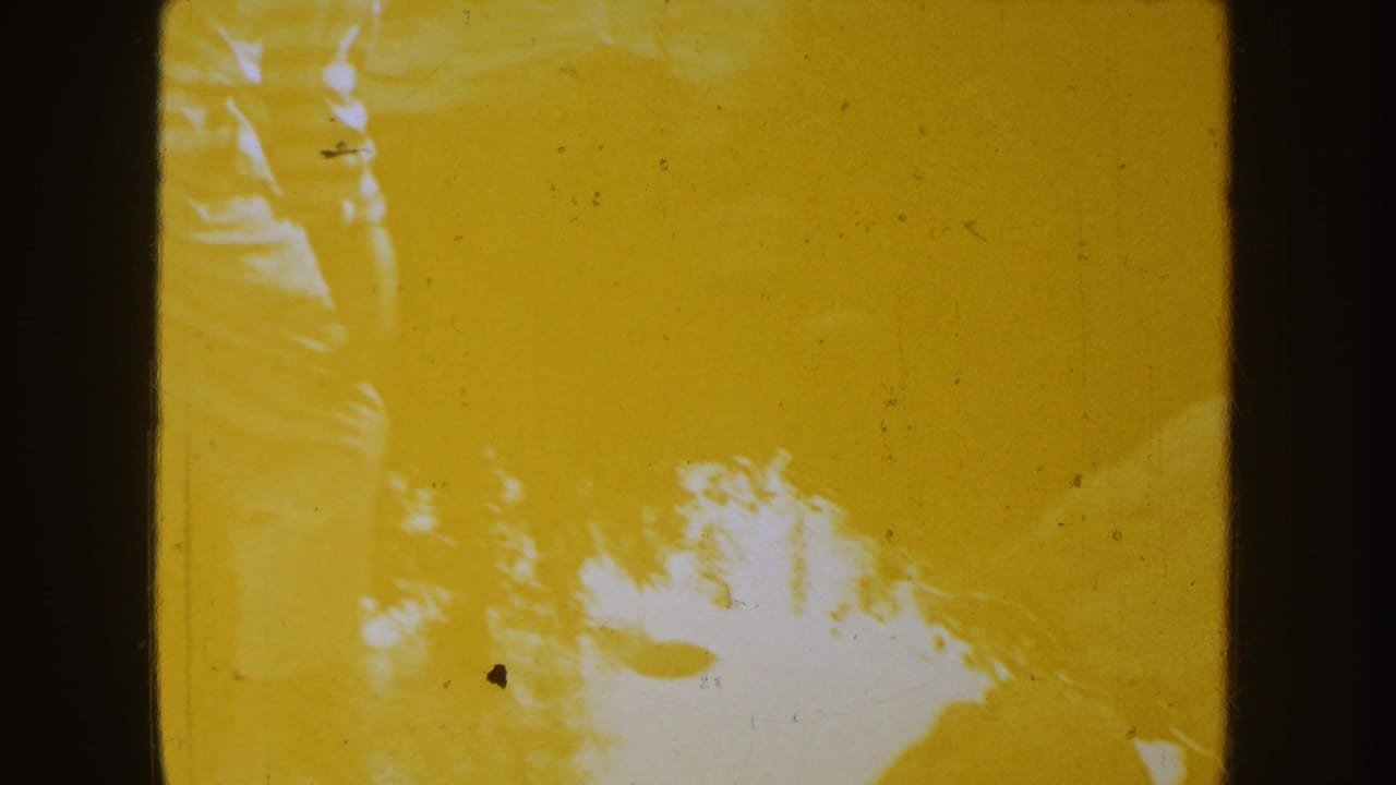 Yellow-tinted 8mm frame with faint tree or sky shapes and visible dust, scratches, and exposure variation.