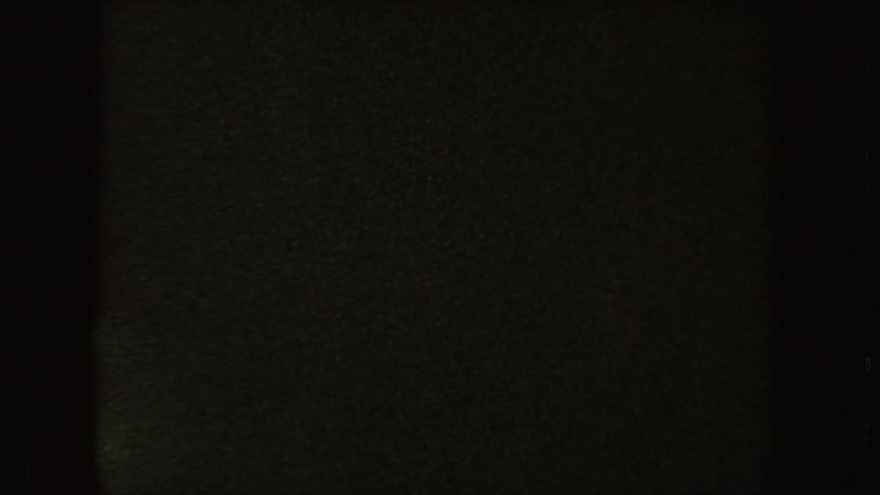 Nearly black end frame from the South Dakota 8mm clip, with faint greenish grain and a visible film border.
