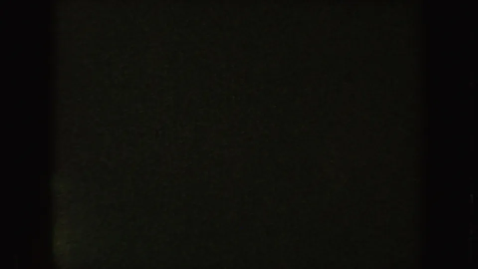 Nearly black end frame from the South Dakota 8mm clip, with faint greenish grain and a visible film border.