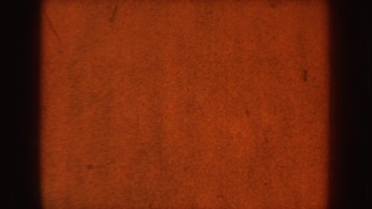 Mostly obscured 8mm frame with orange exposure and dark film edge.