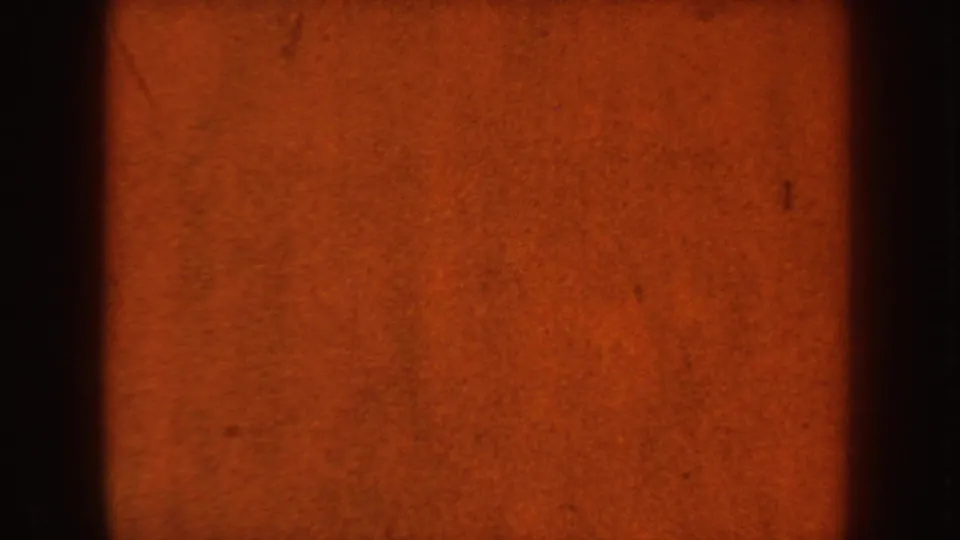 Mostly obscured 1954 8mm frame showing orange exposure, dark gate shadow, and little identifiable scene detail.