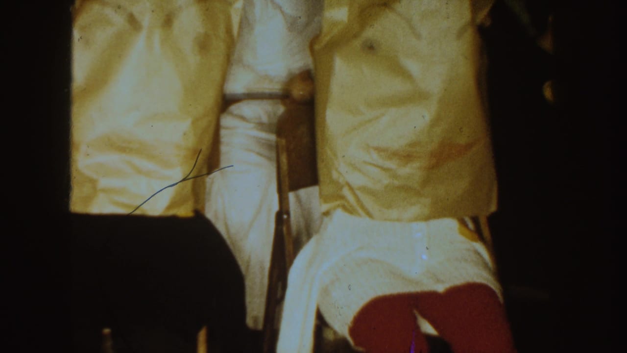 Final 1954 South Dakota frame showing covered seated figures, a person in white, and dark foreground silhouettes during the indoor ritual.