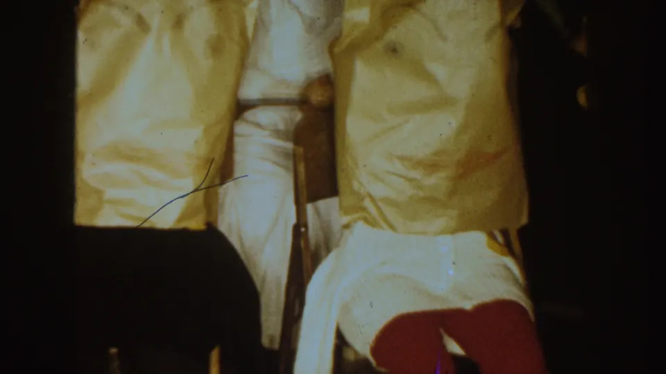 Final 1954 South Dakota frame showing covered seated figures, a person in white, and dark foreground silhouettes during the indoor ritual.