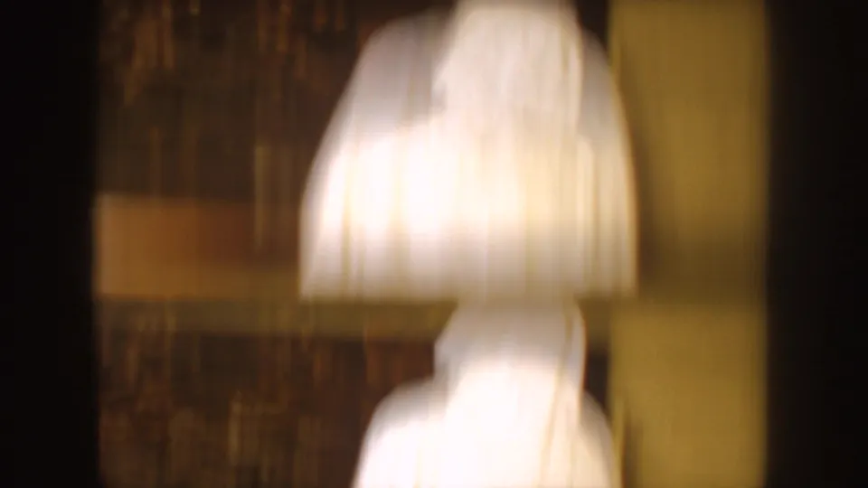 Soft, blurred 8mm frame from the 1954 South Dakota clip showing white robed forms inside a dark private interior.