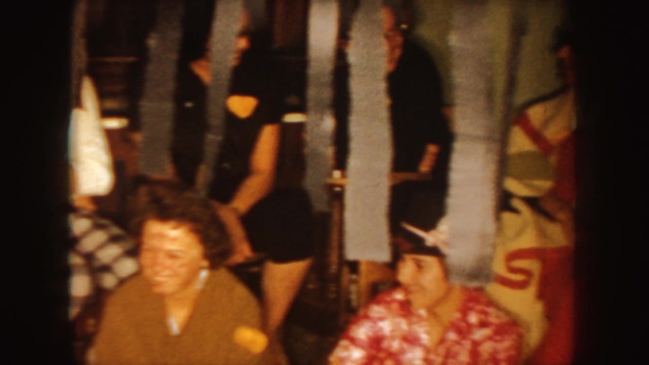 Smiling adults and masked partygoer seated in a decorated interior.