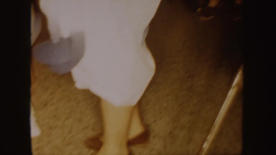 A white-clad figure is partly visible from the side in a 1954 South Dakota indoor home-movie frame.