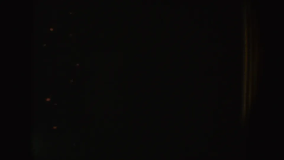 The clip ends on a mostly dark 8mm frame with faint interior detail and visible film grain.