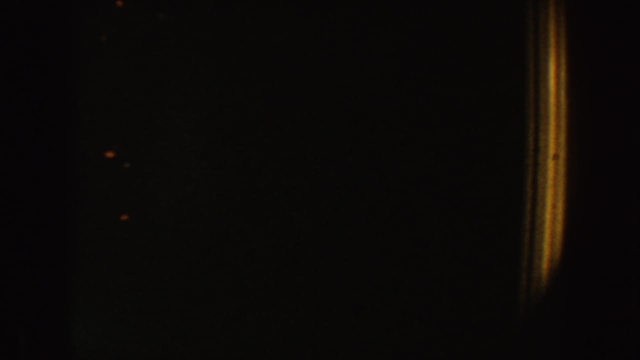 Dark frame with a faint vertical division and scattered warm specks.