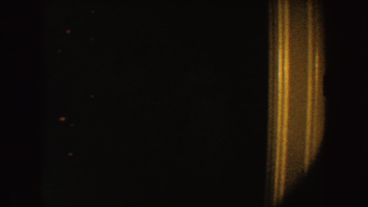 A grainy 1954 South Dakota 8mm frame showing tan vertical trim against a very dark interior.