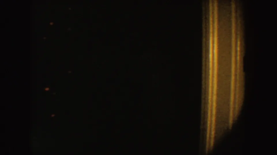 A grainy 1954 South Dakota 8mm frame showing tan vertical trim against a very dark interior.