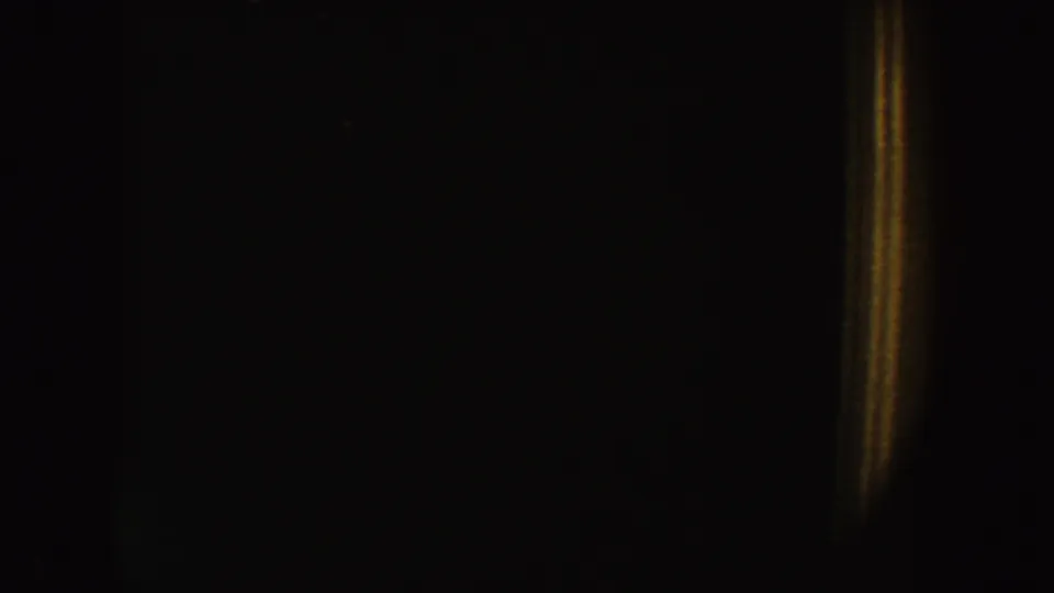 1954 South Dakota 8mm frame showing a dim interior, warm vertical glow, and faint rectangular dark areas.