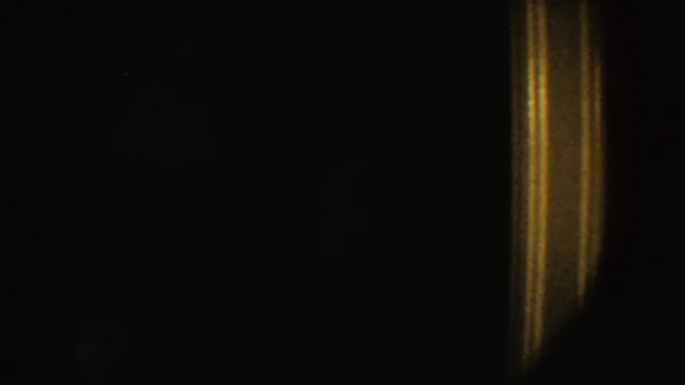 Underexposed 1954 South Dakota home-movie frame with a warm door-like light strip in a dark interior.