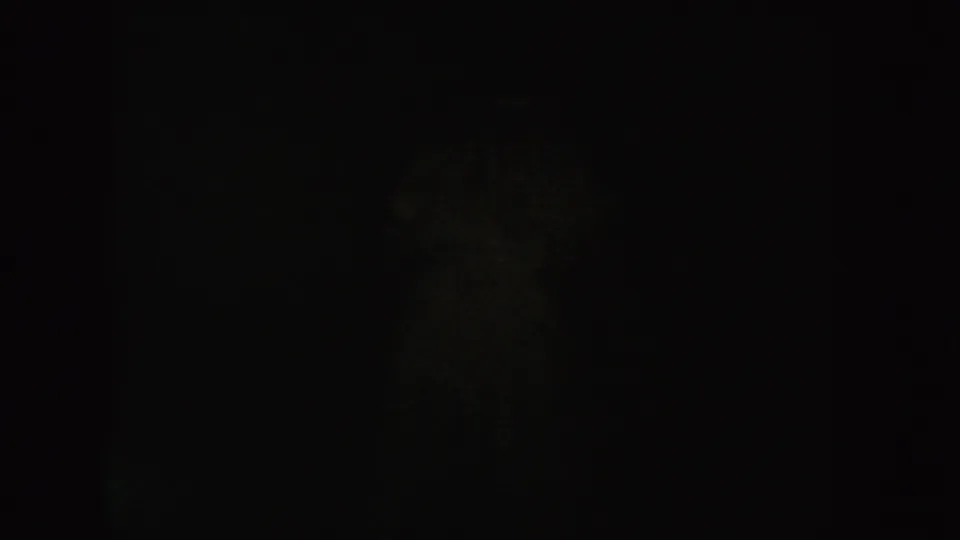 Underexposed 1954 South Dakota 8mm frame showing a mostly black interior with faint shadow texture and no identifiable person.