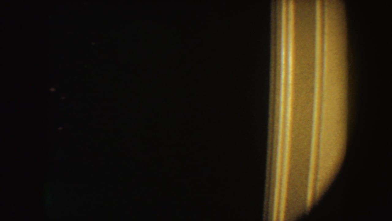 1954 South Dakota 8mm frame showing a dark interior with a bright warm vertical edge on the right and no identifiable figure.