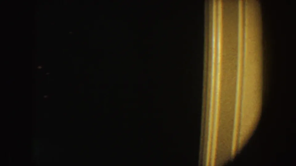 1954 South Dakota 8mm frame showing a dark interior with a bright warm vertical edge on the right and no identifiable figure.