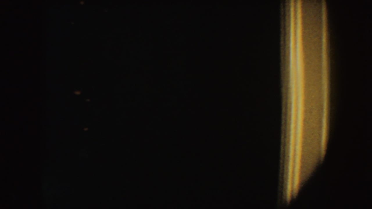 Very dark frame with faint shadows and a warm vertical light at the right side.
